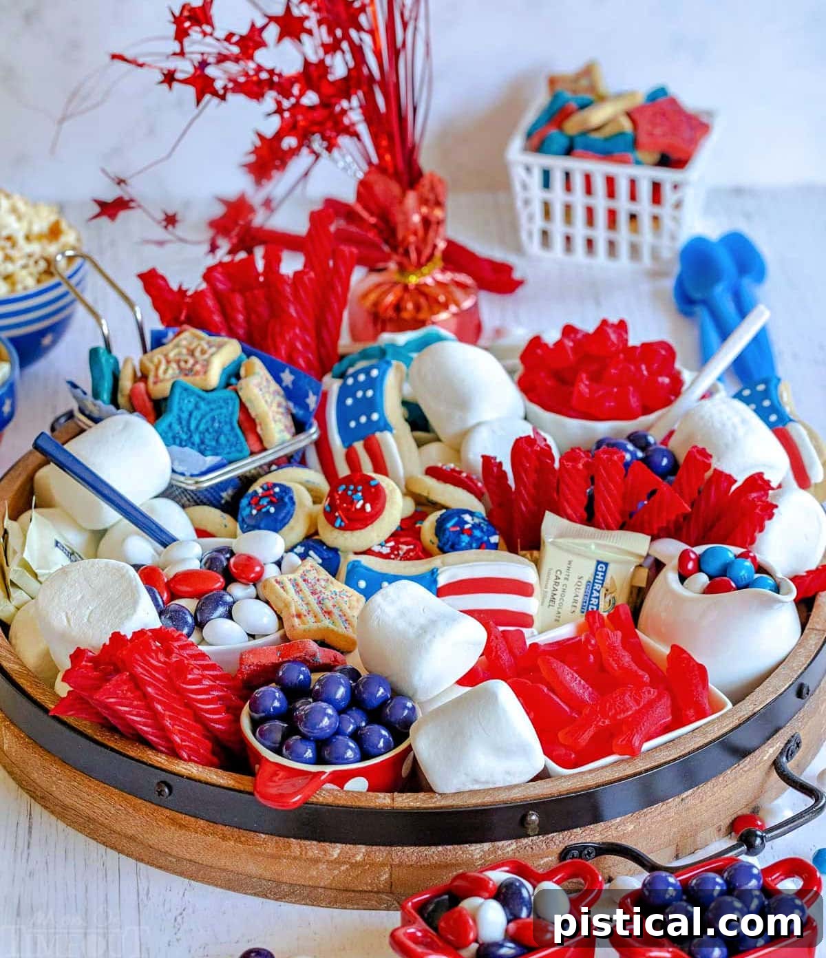 Red, White & Blue Grazing Board 3 angled front view of round wood board with lots of red, white and blue treats for the holiday. marshmallows, cookies, and candies on the board.