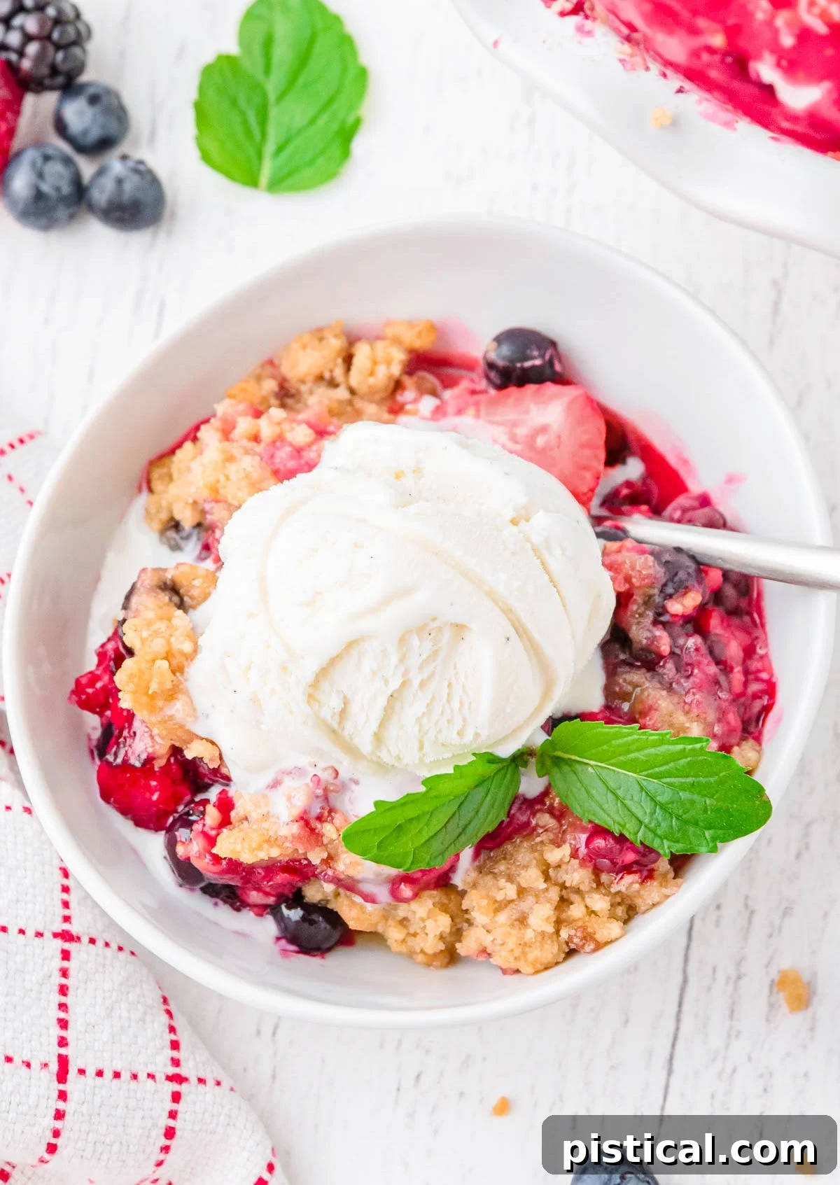 A close-up, top-down view of a pristine white bowl filled with a luscious berry crisp, elegantly crowned with a melting scoop of creamy vanilla ice cream, promising a delightful dessert experience.