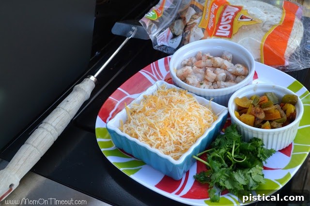 All quesadilla fillings assembled: chopped grilled shrimp, shredded cheese, cilantro, and grilled peppers and onions