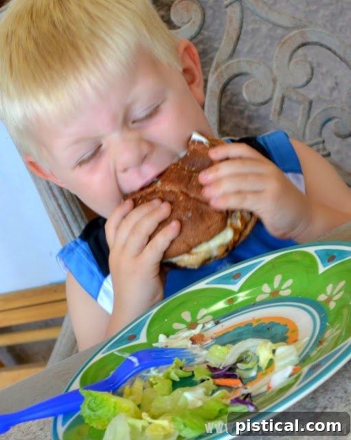 A child happily eating a Teriyaki Pineapple Turkey Burger, showing pure delight.