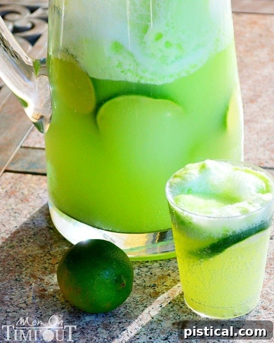 Lemon Lime Party Punch | MomOnTimeout.com Made with lime sherbet this punch is always a crowd pleaser! #beverage #punch Close-up of a glass of frothy Lemon Lime Party Punch, garnished with a fresh lime slice, highlighting its refreshing appeal.