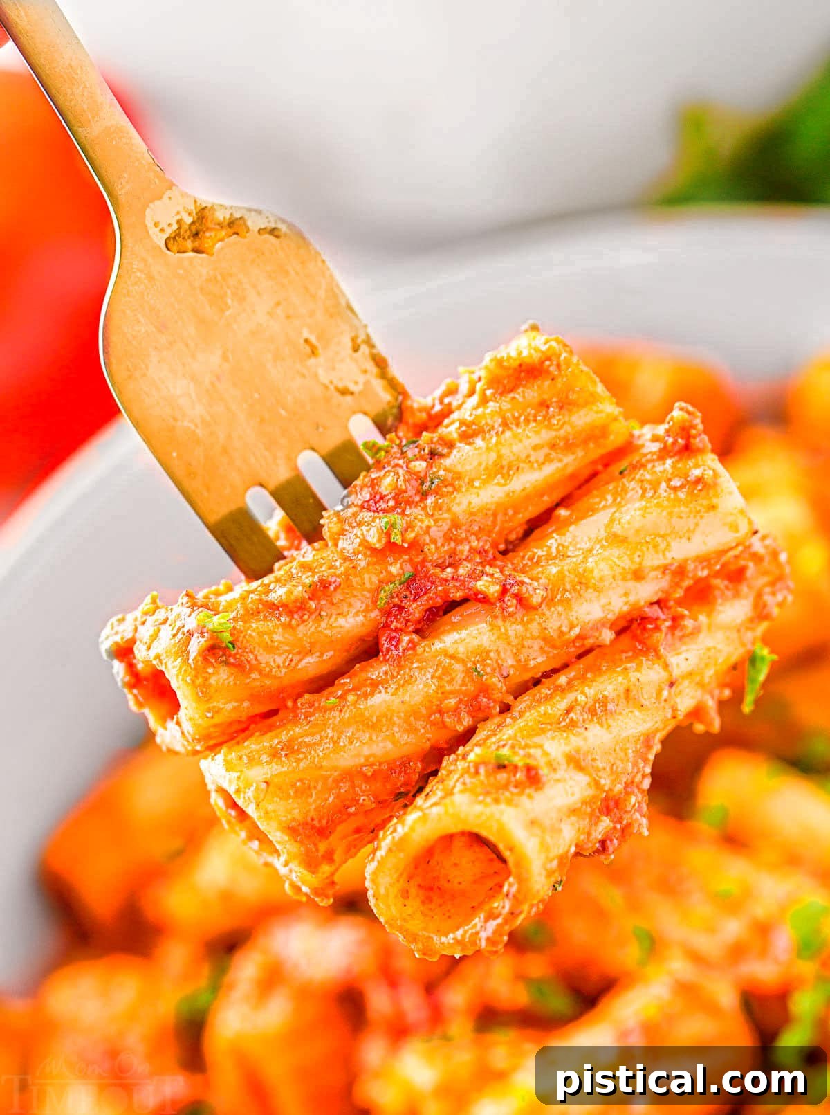 fork with three pieces of pasta on it held above a bowl.