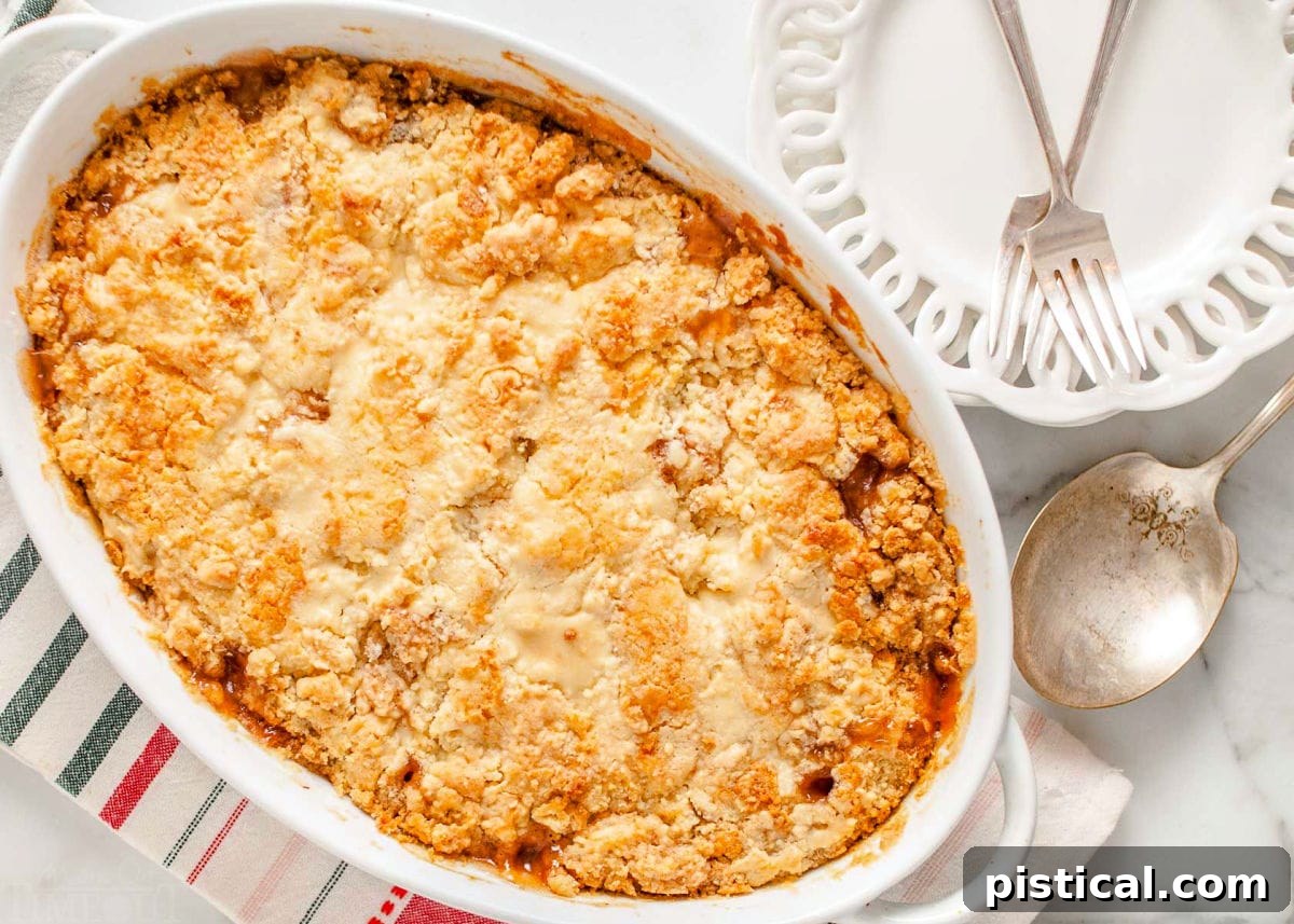 Golden Apple Cobbler Delight 3 cooked apple cobbler in a white baking dish with two white plates and fork sitting off to the side.