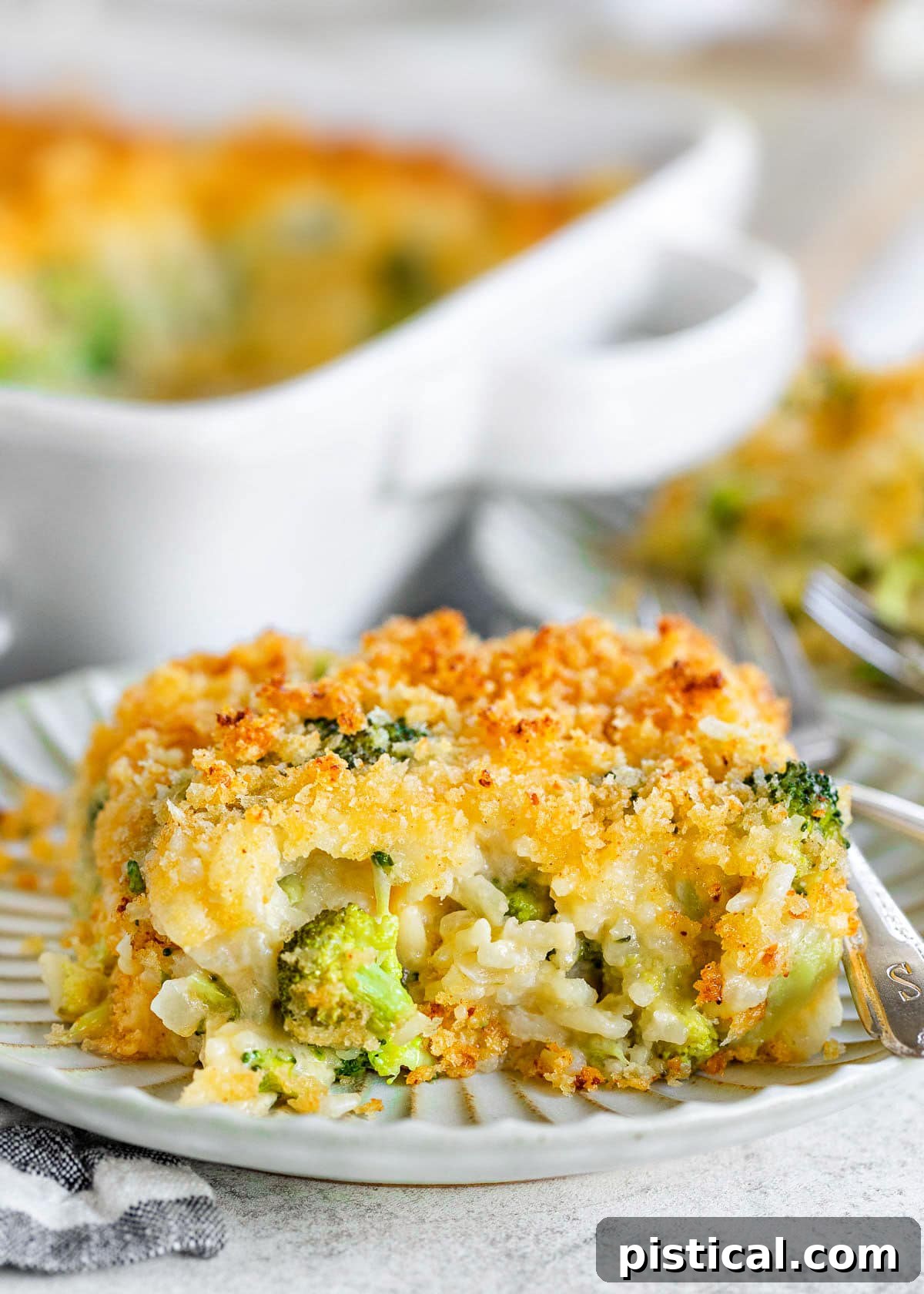 serving of broccoli rice casserole on a small decorative white plate with the casserole dish in the background.
