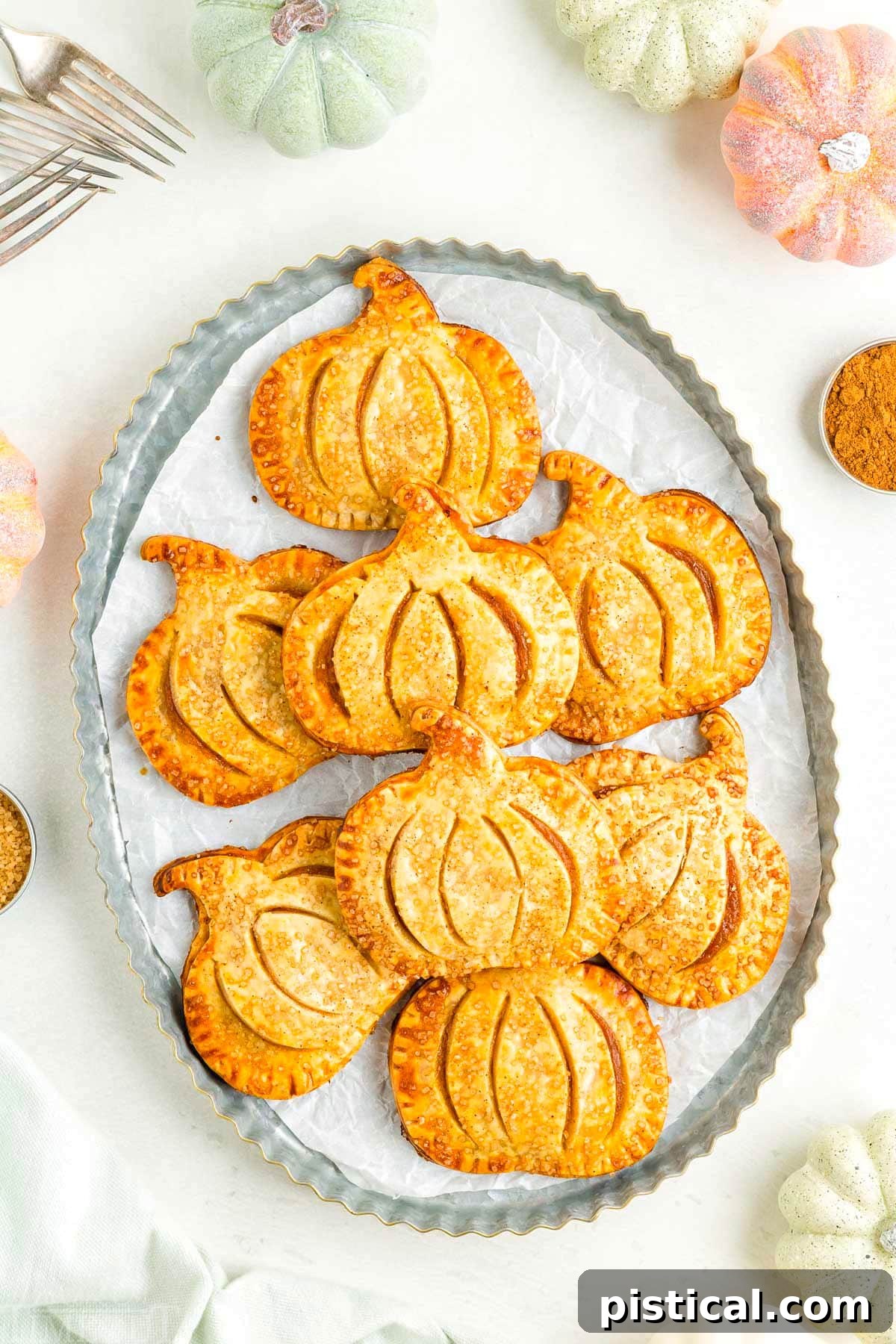 An inviting top-down view of perfectly arranged pumpkin hand pies on a rustic metal platter, ready for serving.