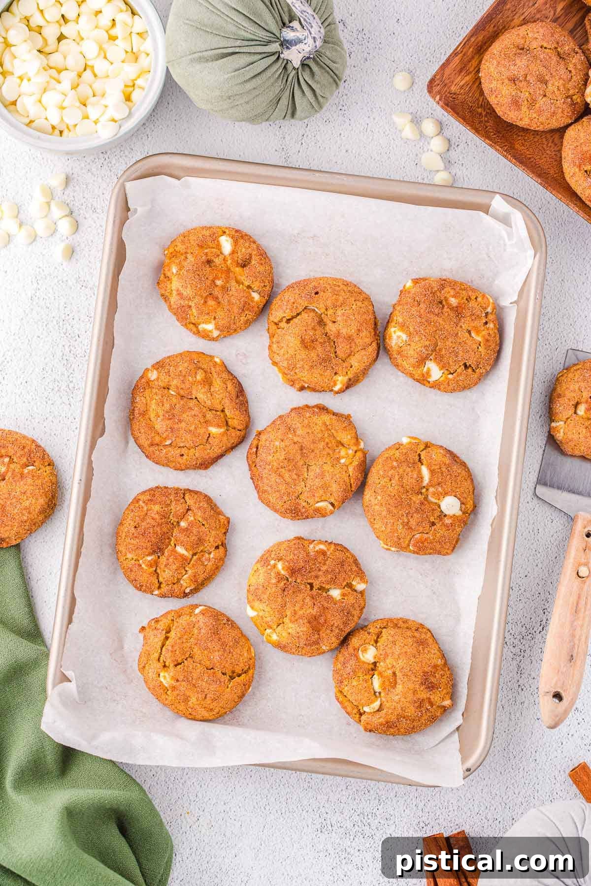 Top down look at cookies baked on a baking sheet, ready to enjoy. A green napkin is in the bottom corner and more cookies are scattered about.