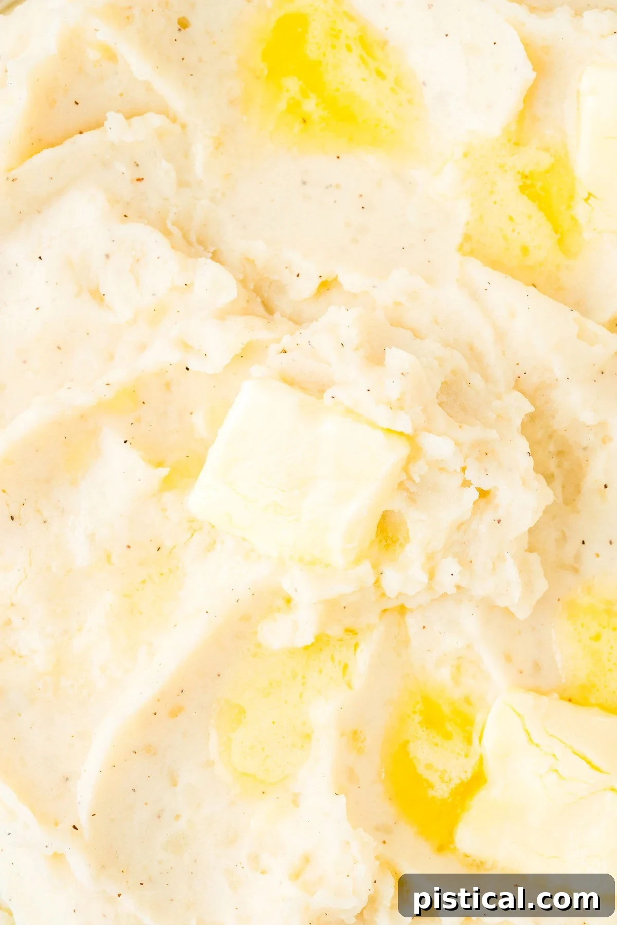 A close-up, mouth-watering view of rich, creamy Instant Pot Mashed Potatoes, generously topped with an abundant amount of melting butter, highlighting its smooth texture and comforting appeal.