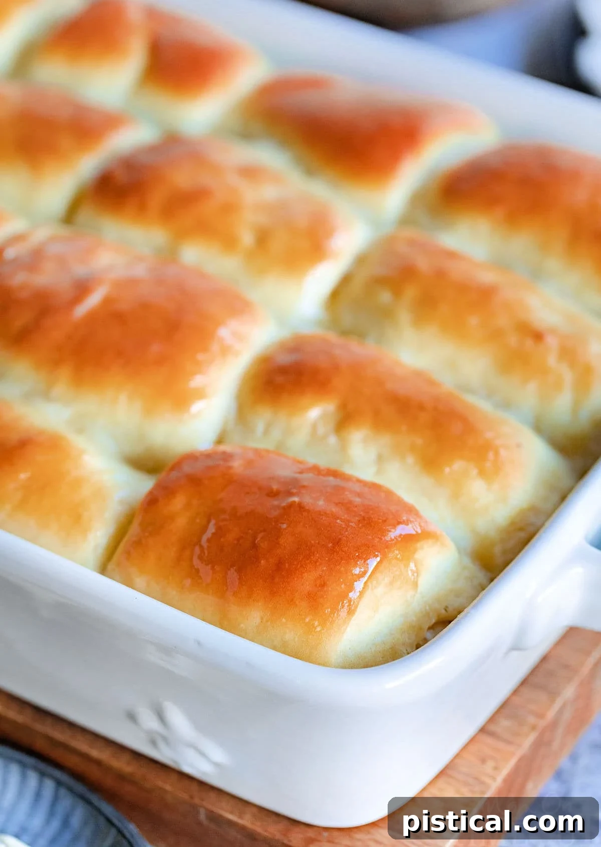golden brown parker house rolls slathered with butter and still in the white baking dish.