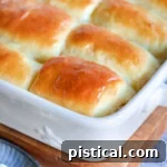 golden brown parker house rolls slathered with butter and still in the white baking dish.