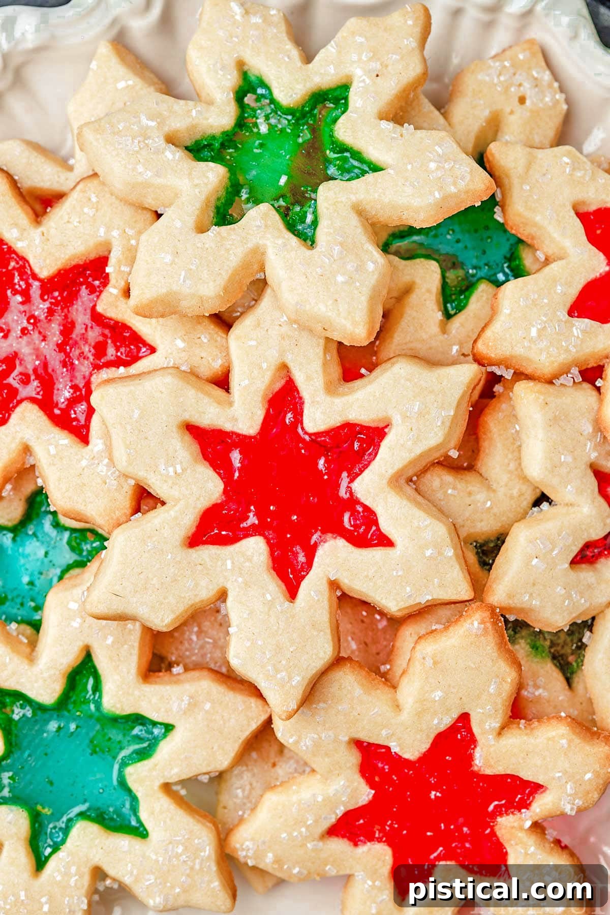 Crystal Window Bites 4 top down look at tray loaded with stained glass cookies with red and green centers cut into snowflake shapes.