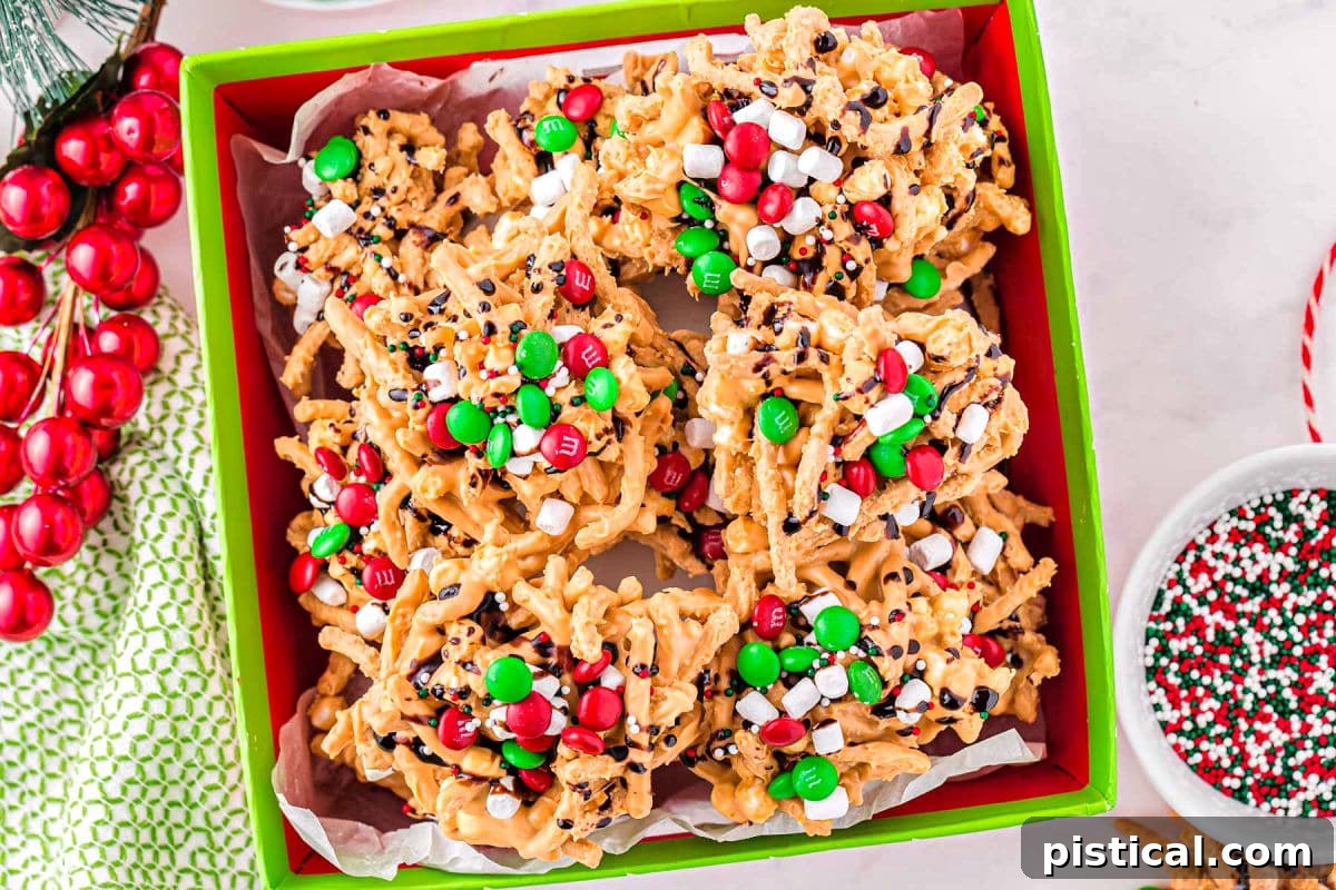 Stacks of Buddy the Elf Haystack candies, decorated with chocolate, marshmallows, and M&M's, arranged in a festive Christmas box.