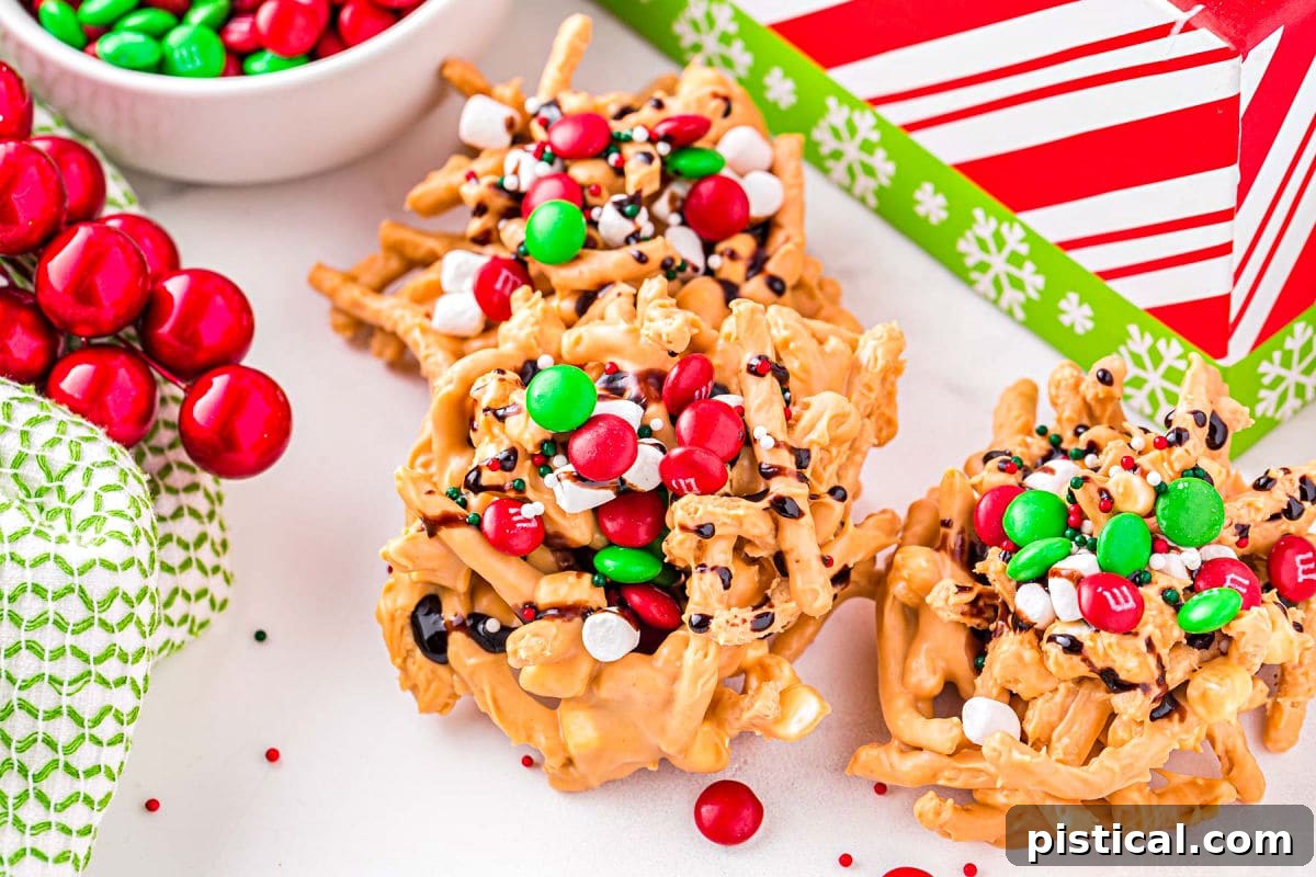 Three Buddy the Elf Haystack candies, covered in marshmallows and chocolate syrup, resting on a white surface in front of a red and white striped Christmas box.