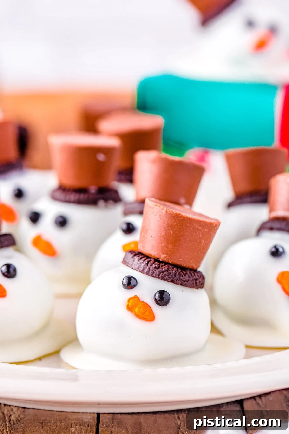 Melting Snowman Oreo Truffles 2 melting snowman oreo balls on a white plate topped with mini oreos and rolo candy.