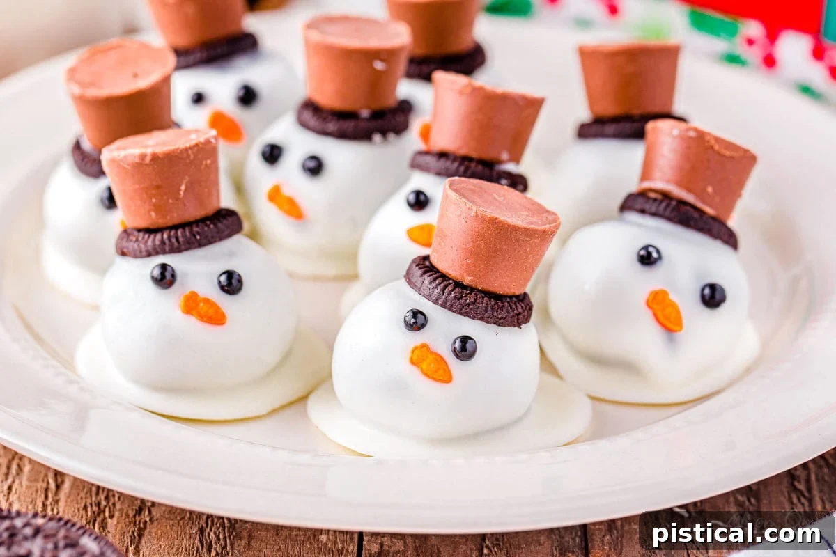 Melting Snowman Oreo Truffles 5 melting snowman oreo balls on a white plate topped with mini oreos and rolo candy.