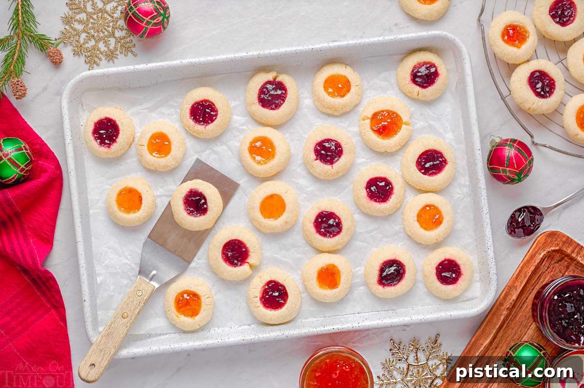 thumbprint cookies on a parchment lined baking sheet with spatula lifting off one cookie.