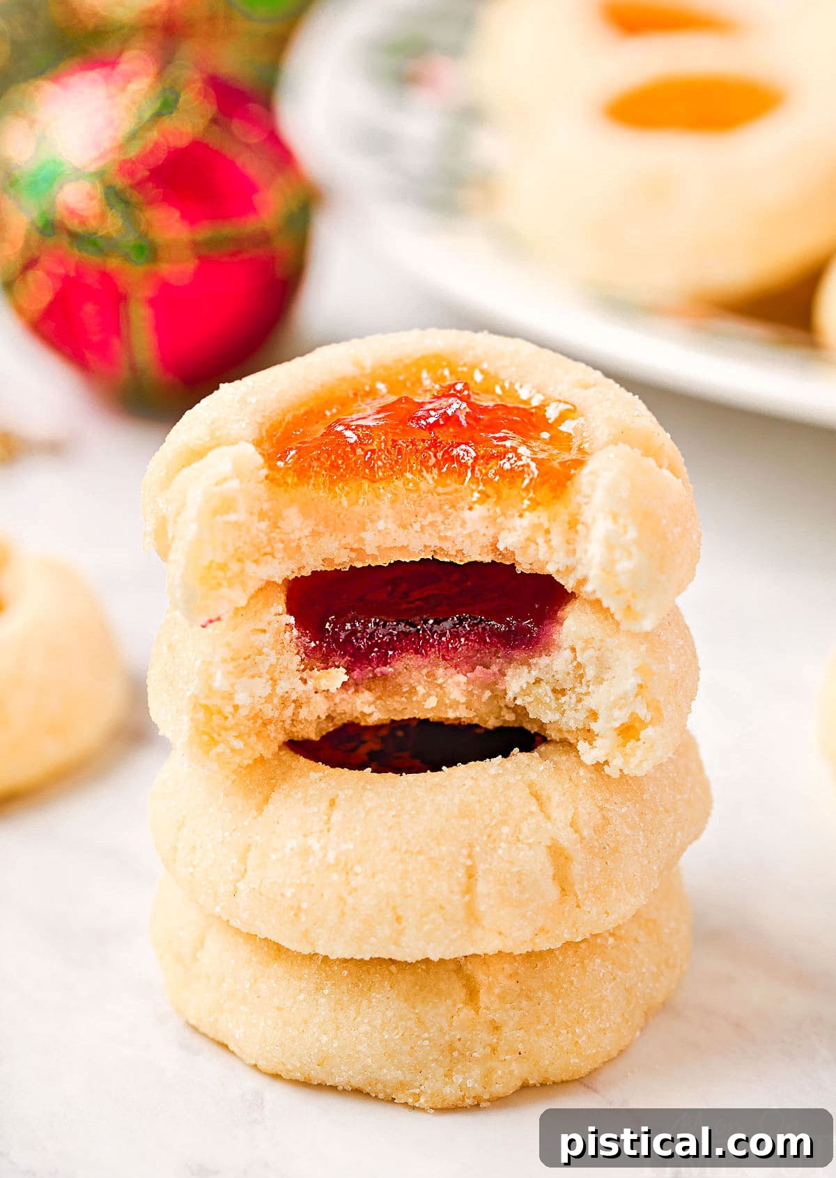 four cookies stacked with jam centers. top two cookies have bites taken out of them.