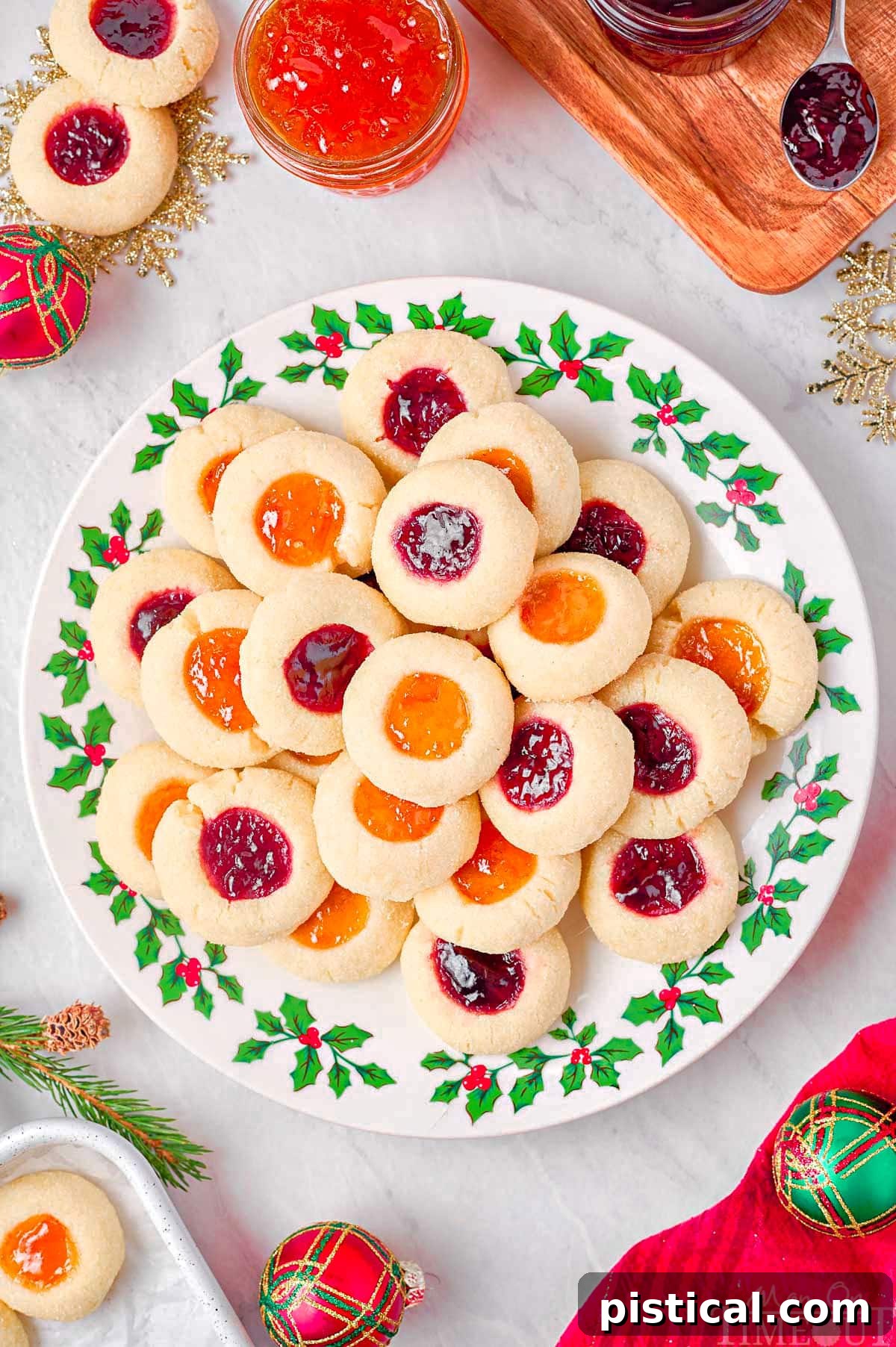 top down look at christmas plate piled high with thumbprint cookies filled with raspberry and apricot jam