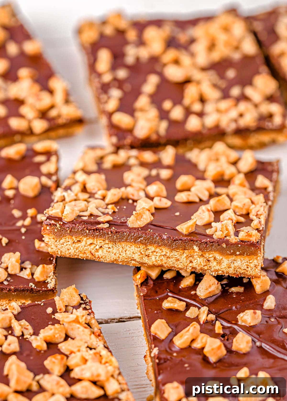 Graham cracker toffee laid out on parchment paper with one square sitting up at an angle, showcasing its golden brown color and chocolate topping.