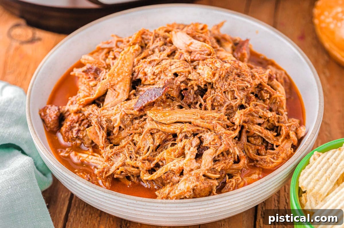 A large, inviting bowl filled with perfectly shredded, tender pulled pork, showcasing its rich texture and readiness to be served.