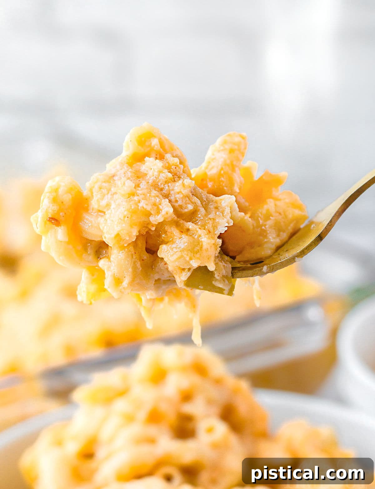 forkful of mac and cheese held above the bowl filled with the mac and cheese.