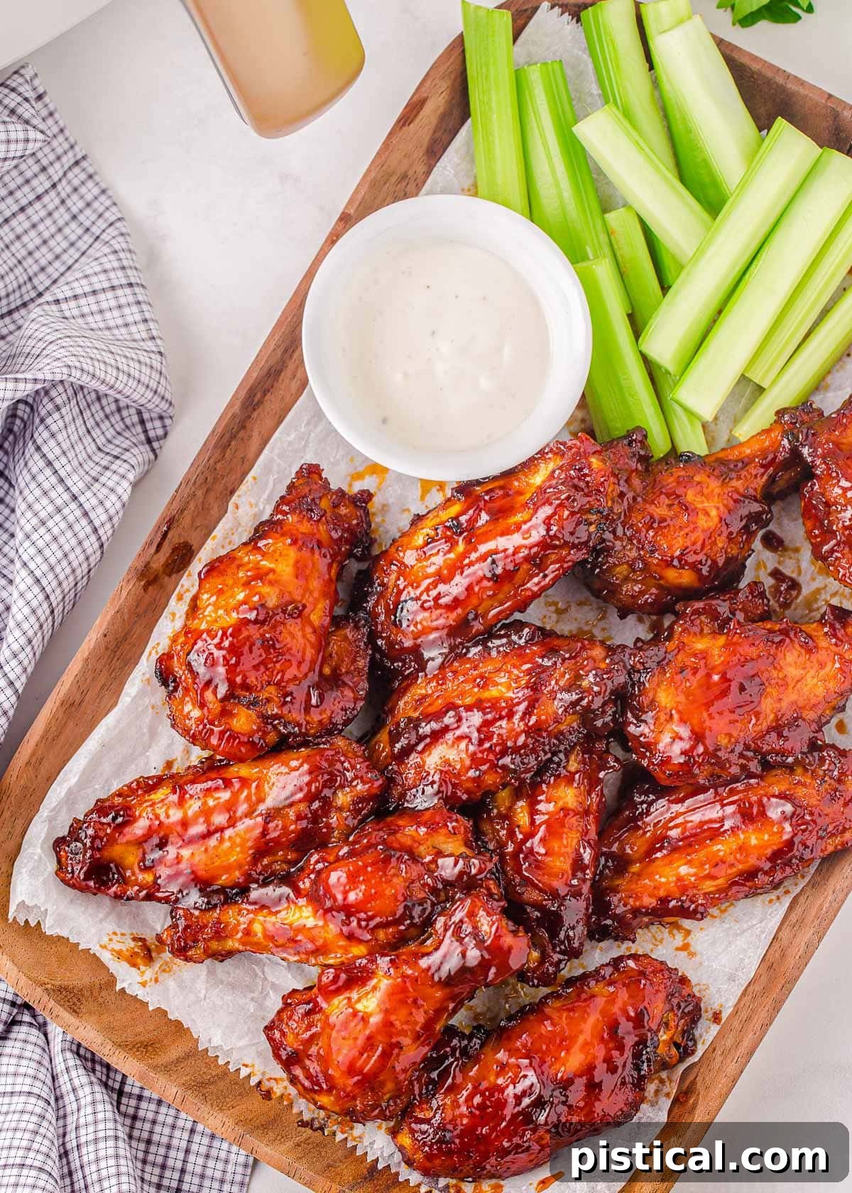 A top-down view of BBQ Air Fryer Chicken Wings arranged on a rustic wooden board, accompanied by fresh celery sticks and a bowl of creamy ranch dressing, highlighting a perfect game day spread.