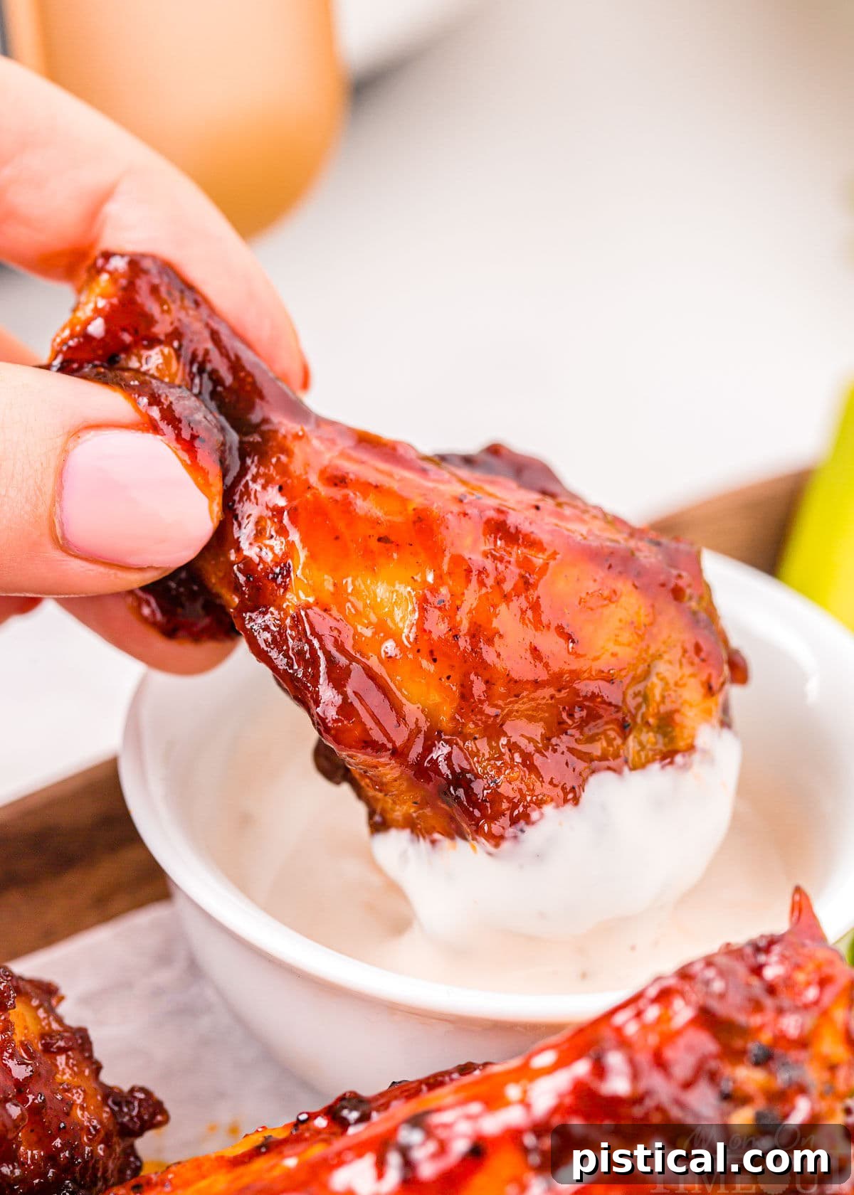 A perfectly crispy BBQ Air Fryer Chicken Wing is being dipped into a bowl of creamy ranch dressing, emphasizing its deliciousness and the classic pairing.