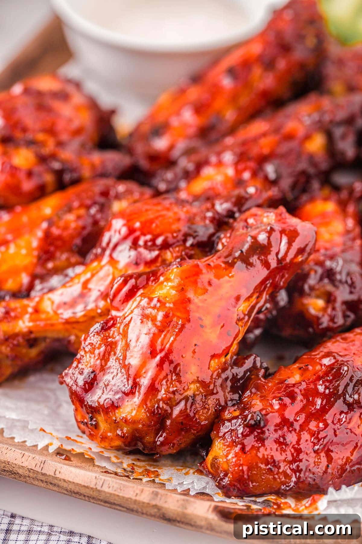 A wooden board filled with freshly made Air Fryer Chicken Wings, brushed with BBQ sauce and garnished with parsley, ready to be served.