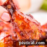 hand holding a chicken wing made in the air fryer and brushed with barbecue sauce.