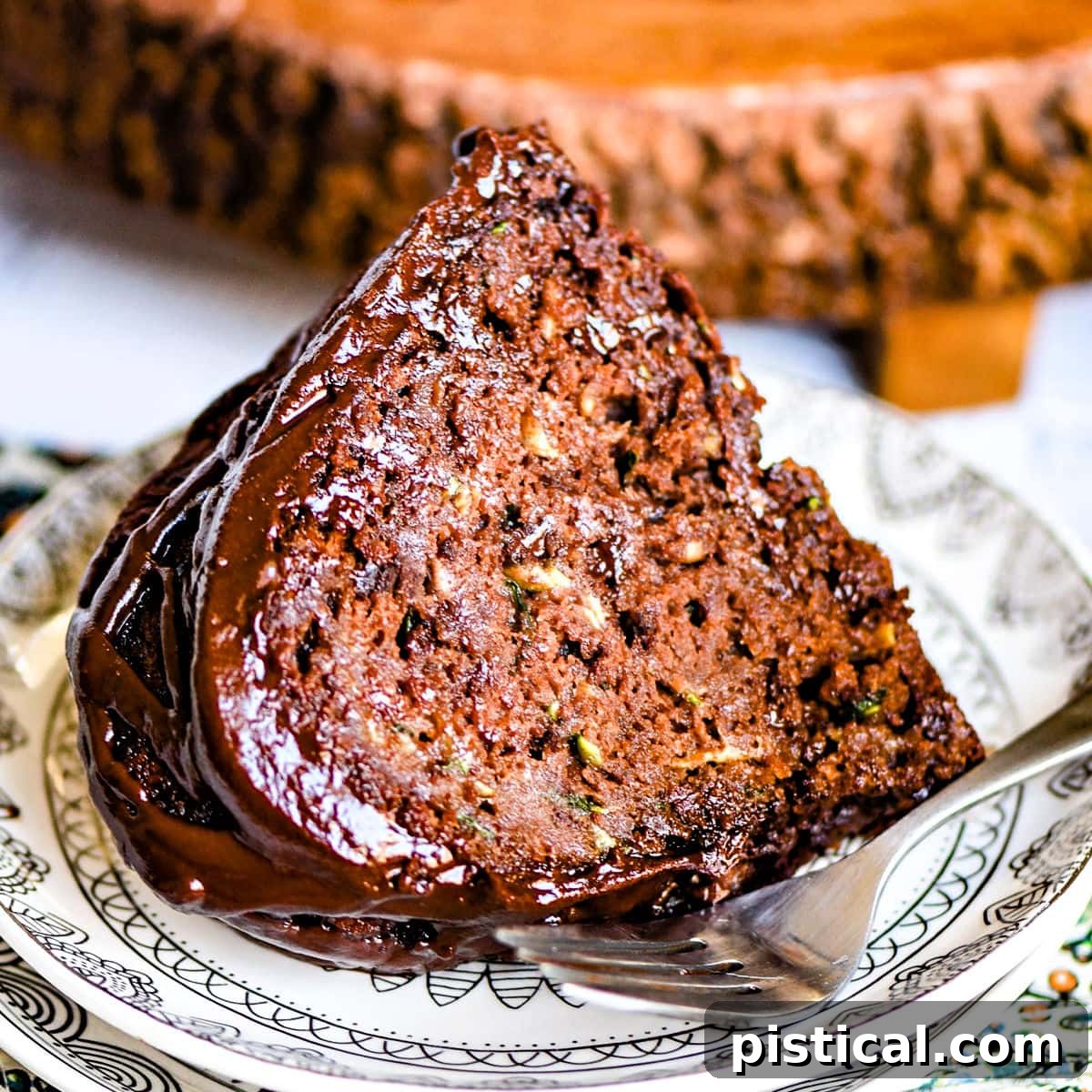 A perfectly portioned slice of chocolate zucchini cake artfully placed on a pristine white plate, showcasing its moist texture and uniform chocolate color.