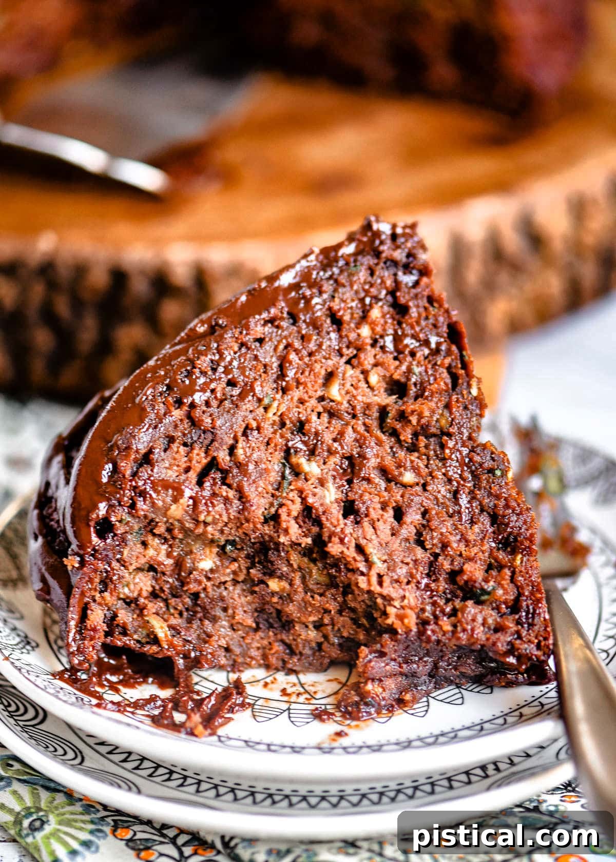 A partially eaten slice of chocolate zucchini cake on a small white plate, showcasing its rich, moist interior after a few delicious bites.