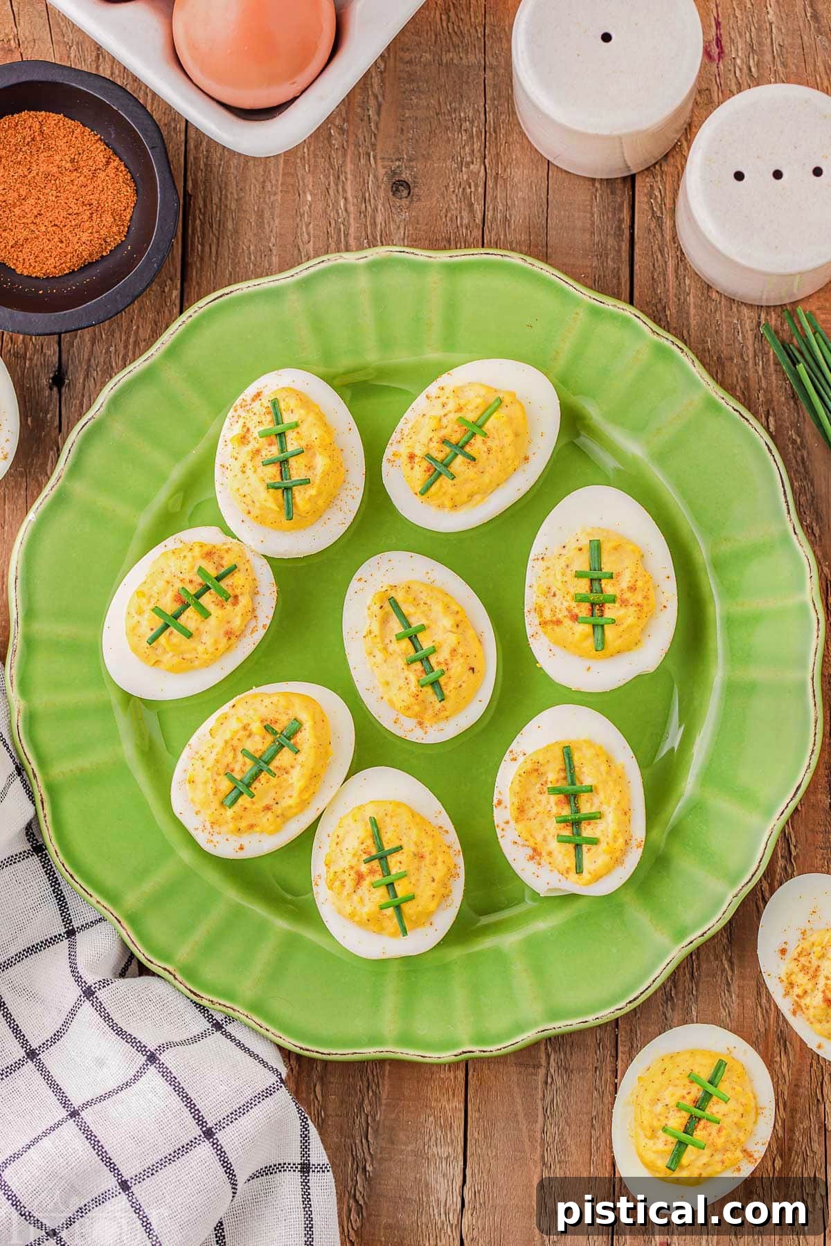 Touchdown Deviled Treats 5 A top-down view of a vibrant green plate generously loaded with deviled eggs, each meticulously decorated to resemble a football.