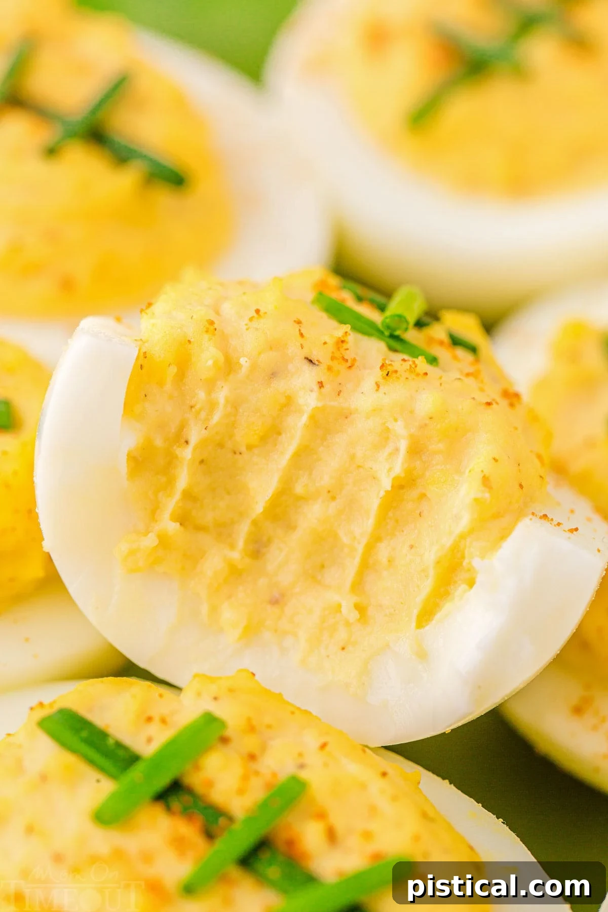 Touchdown Deviled Treats 6 Close-up of football-decorated deviled eggs on a plate, with one egg having a bite taken out of it, showcasing the creamy filling.