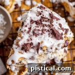 top down view of three coconuts scones stacked on top of each other and topped with coconut icing and chocolate shavings.
