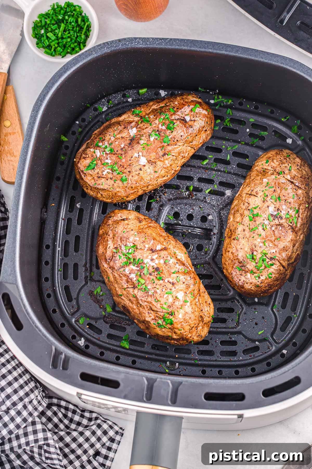 Perfect Air Fryer Baked Potatoes 3 Top down view of three potatoes in an air fryer basket, cooking to perfection.