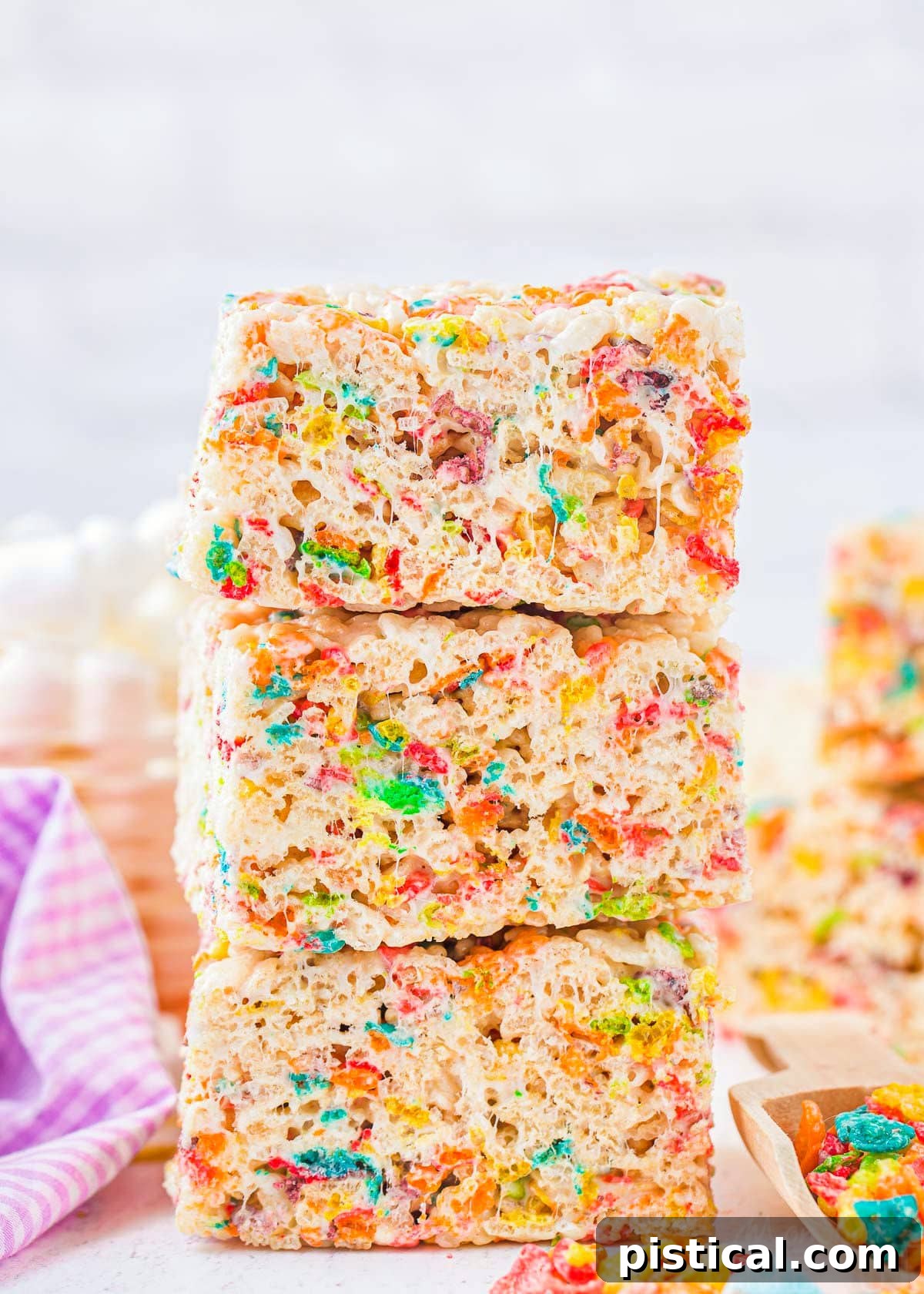 three rainbow rice krispie treats made with fruity pebbles stacked on top of each other.