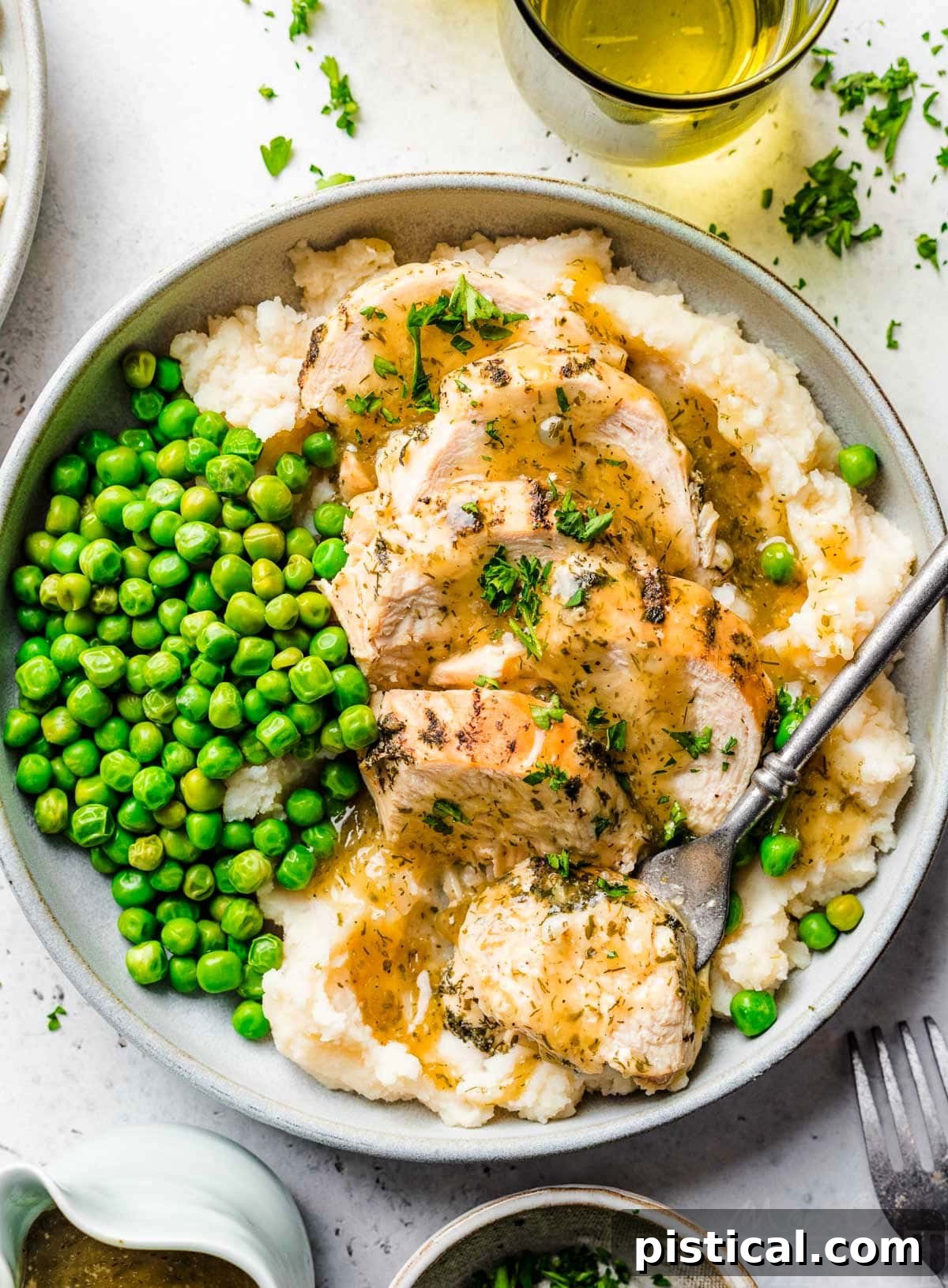 Easy Instant Pot Chicken Breast with Velvety Gravy 2 top down look at instant pot chicken breast sliced sitting on a bed of mashed potatoes with gravy over the top. green peas are also on the plate.