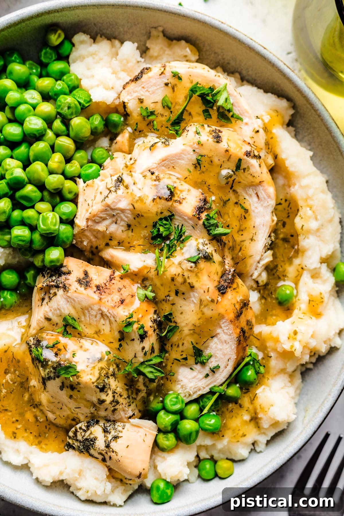 Easy Instant Pot Chicken Breast with Velvety Gravy 3 close up of instant pot chicken breast on plate with mashed potatoes and peas and topped with a cream gravy and freshly chopped parsley.