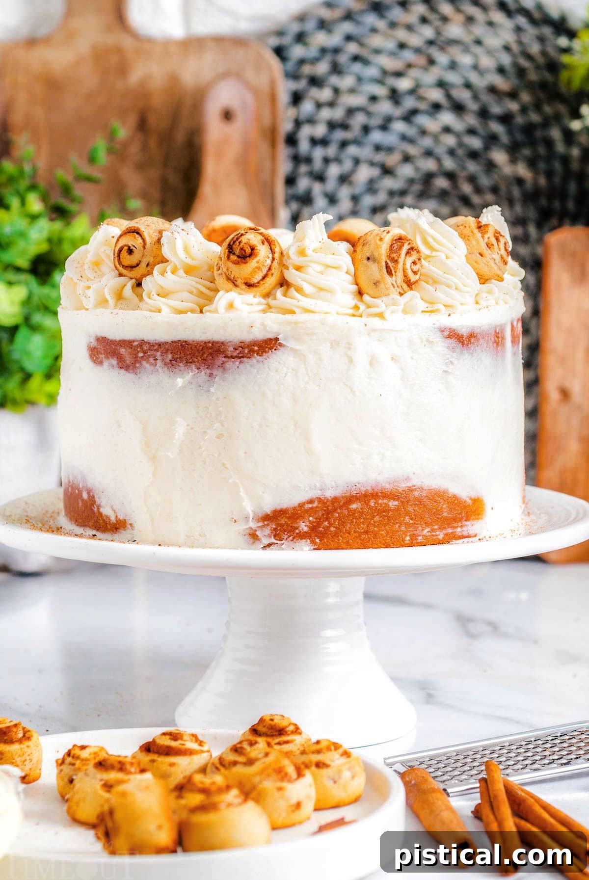 Decadent Cinnamon Swirl Layer Cake 2 A stunning Cinnamon Roll Layer Cake on a white cake stand, generously topped with creamy cream cheese frosting and adorned with miniature cinnamon rolls. This delicious cake is a perfect blend of comfort and elegance.