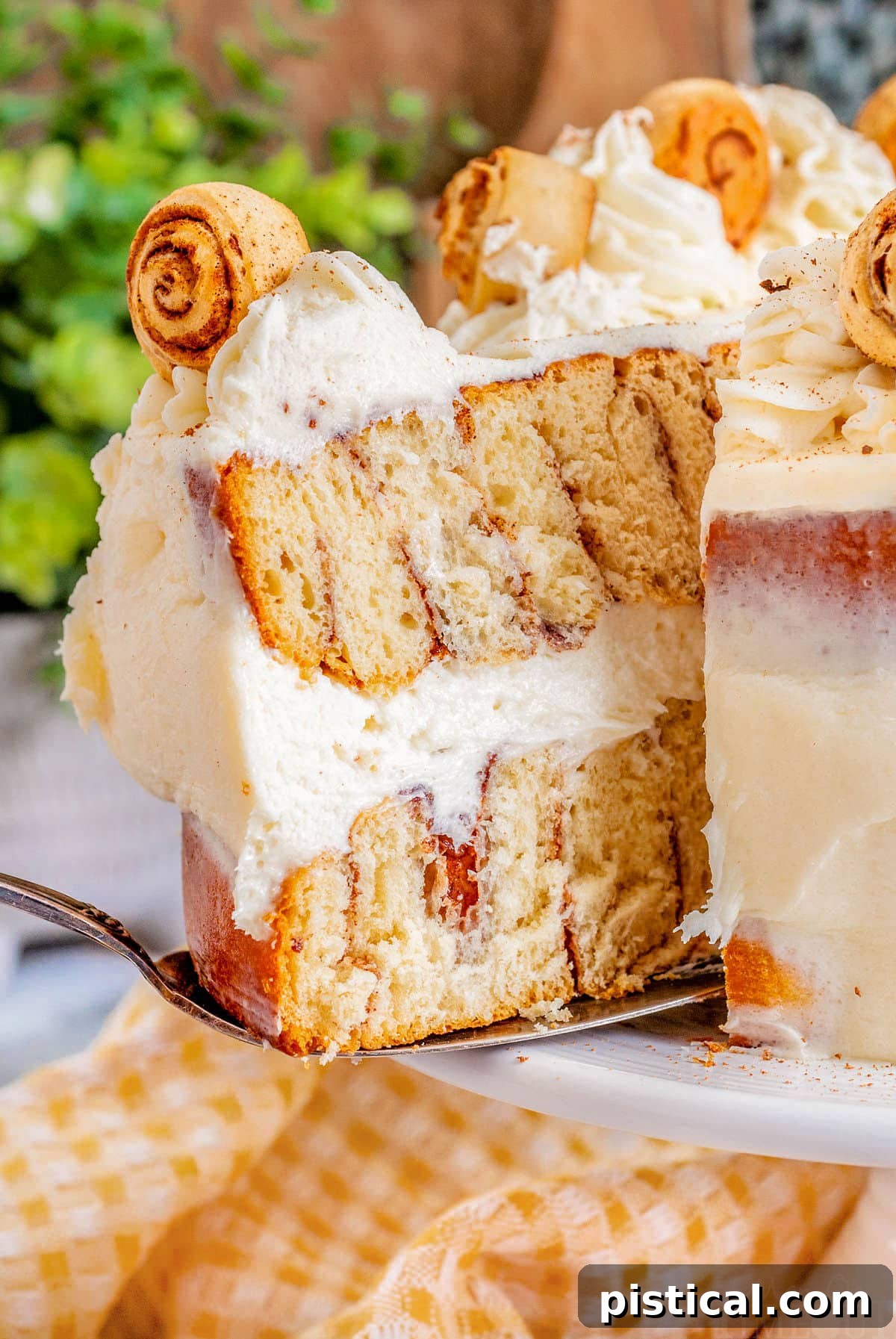 Decadent Cinnamon Swirl Layer Cake 4 A large slice of the Cinnamon Roll Layer Cake being carefully removed from a white cake plate, revealing the intricate cinnamon swirls within its soft layers.