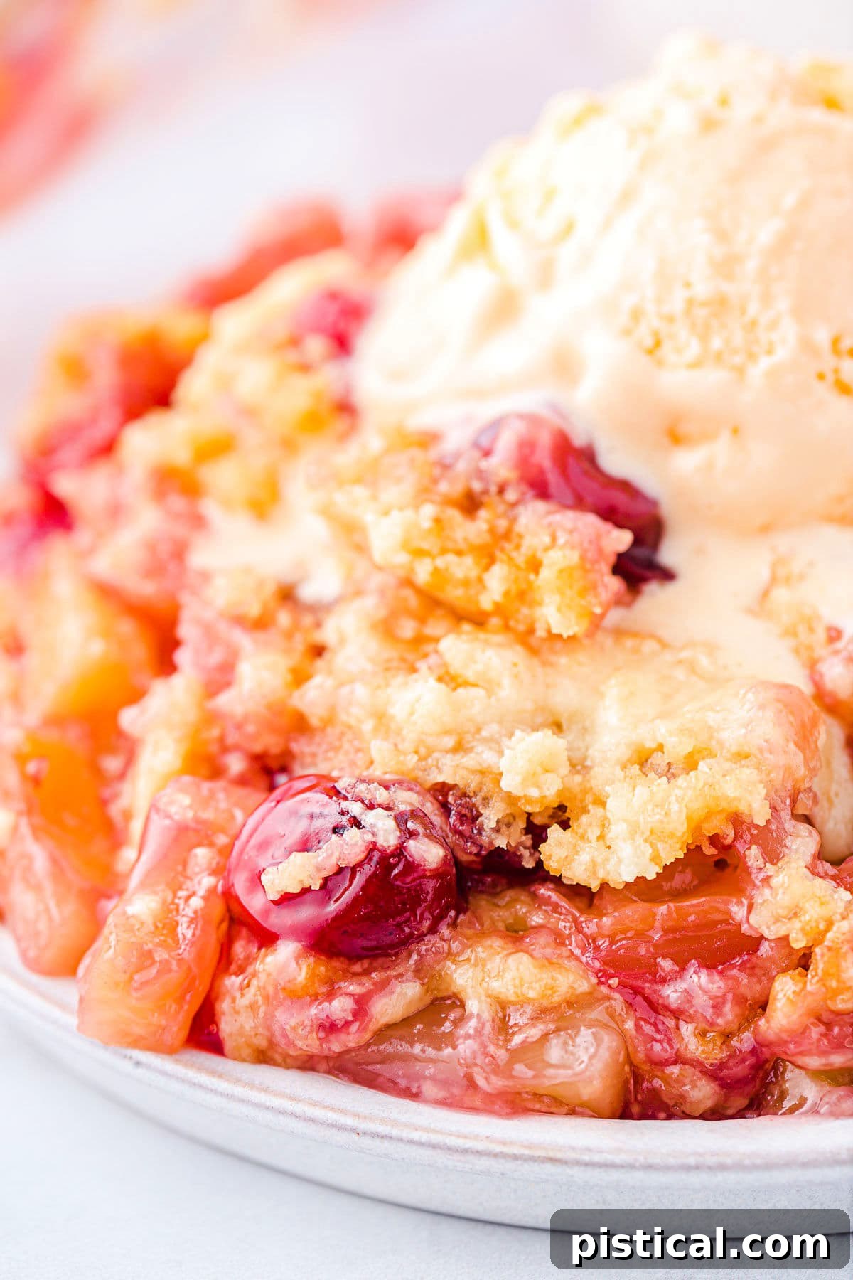 Tropical Cherry Pineapple Delight 2 A slice of cherry pineapple dump cake topped with melting vanilla ice cream, showing visible cherries and pineapple chunks.