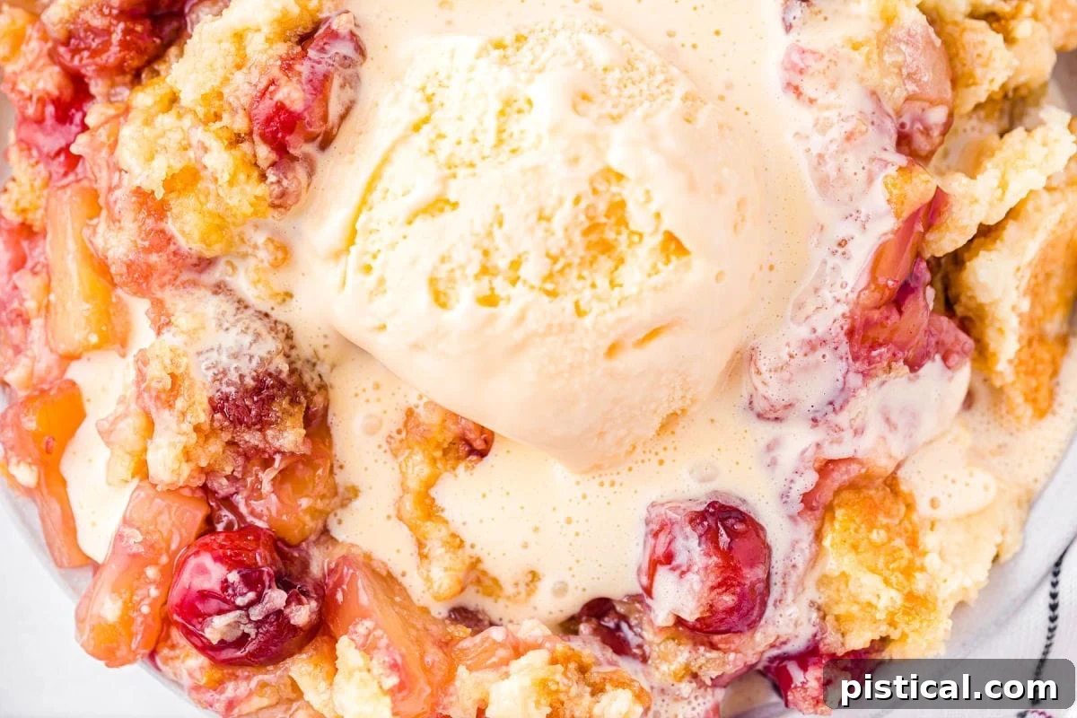 Tropical Cherry Pineapple Delight 3 Close-up of a serving of cherry pineapple dump cake with a melting scoop of vanilla ice cream on top.