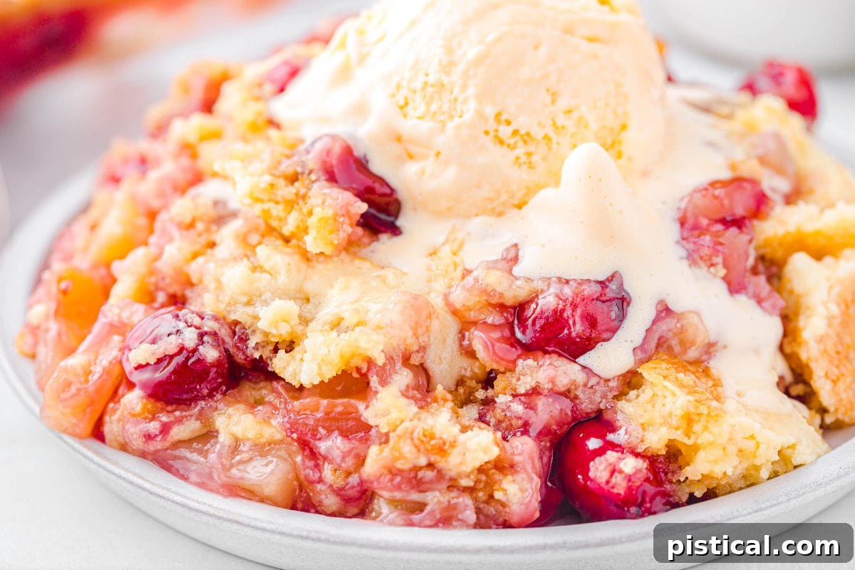 Tropical Cherry Pineapple Delight 5 A generous serving of pineapple cherry dump cake on a shallow plate, topped with a scoop of melting vanilla ice cream.