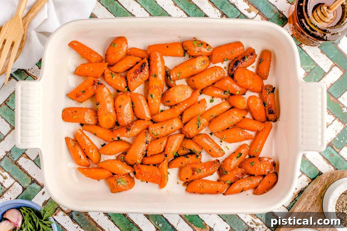 Top-down view of golden honey roasted carrots served in a rustic white baking dish, ready for the table.