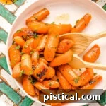 honey glazed carrots on a round white plate garnished with fresh parsley.