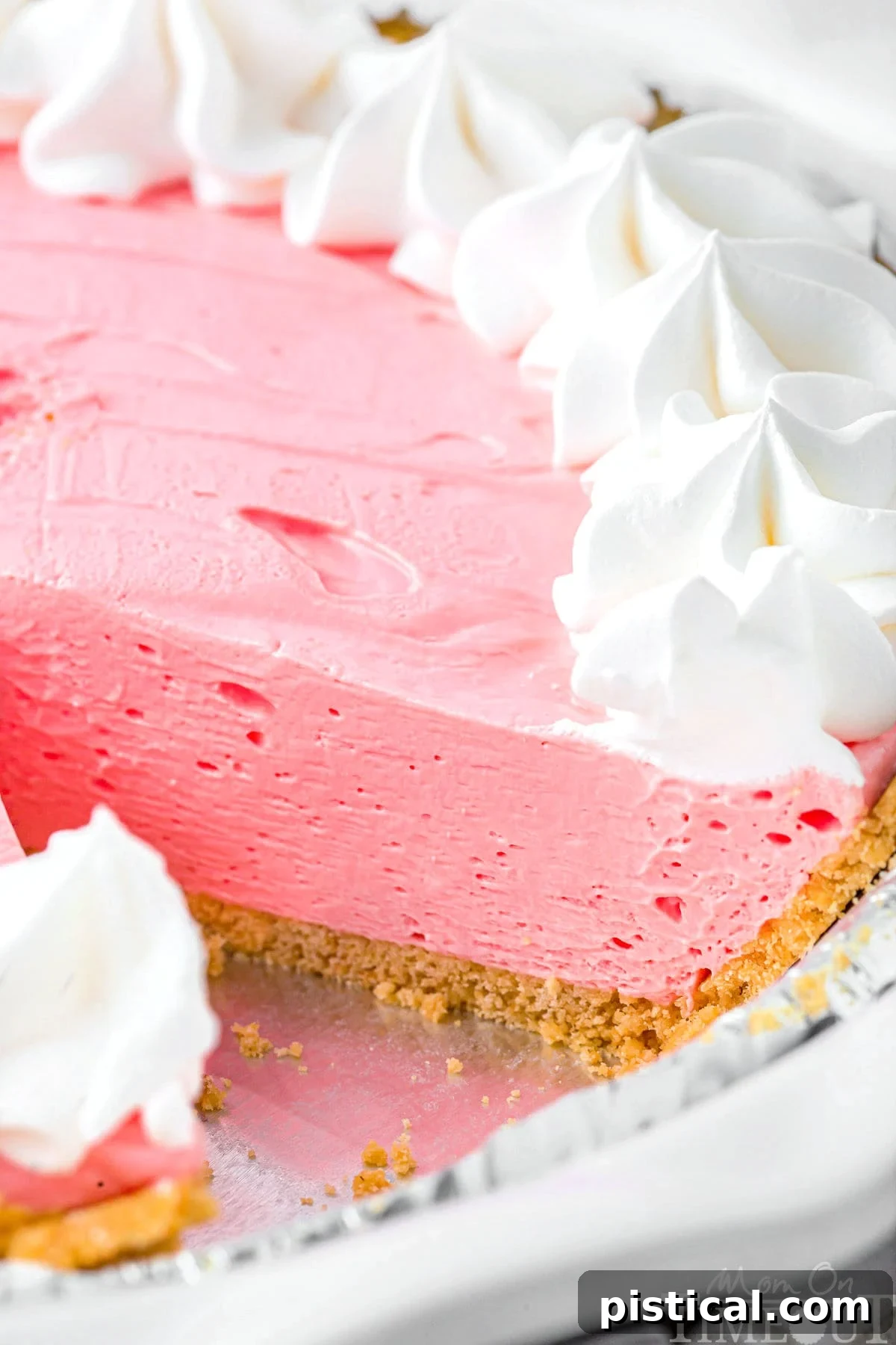 A vibrant strawberry Kool Aid Pie showcased in a classic golden graham cracker crust, with one tempting slice already removed and ready to enjoy, highlighting its creamy filling.