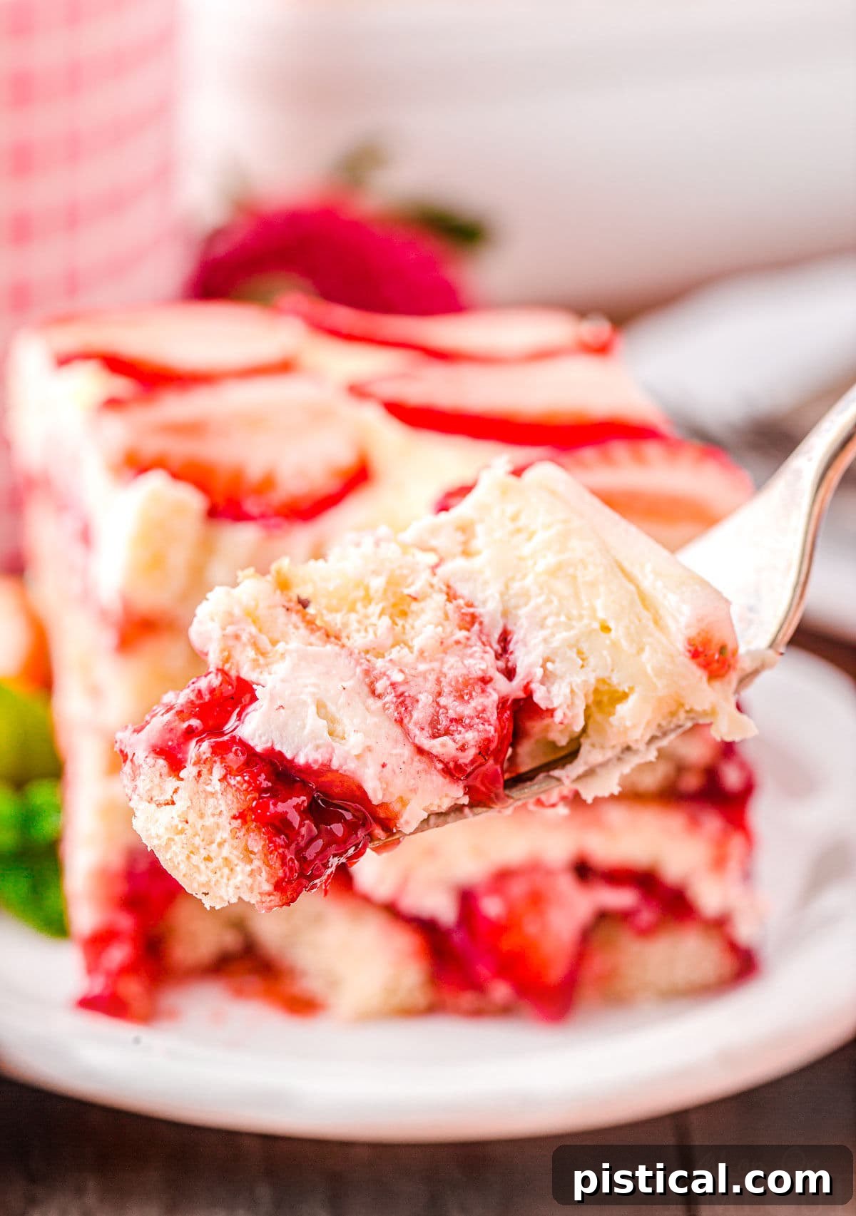 Strawberry Dream Tiramisu 3 A fork lifts a bite of Strawberry Tiramisu, revealing its beautifully crafted layers of cream and fruit-soaked ladyfingers.