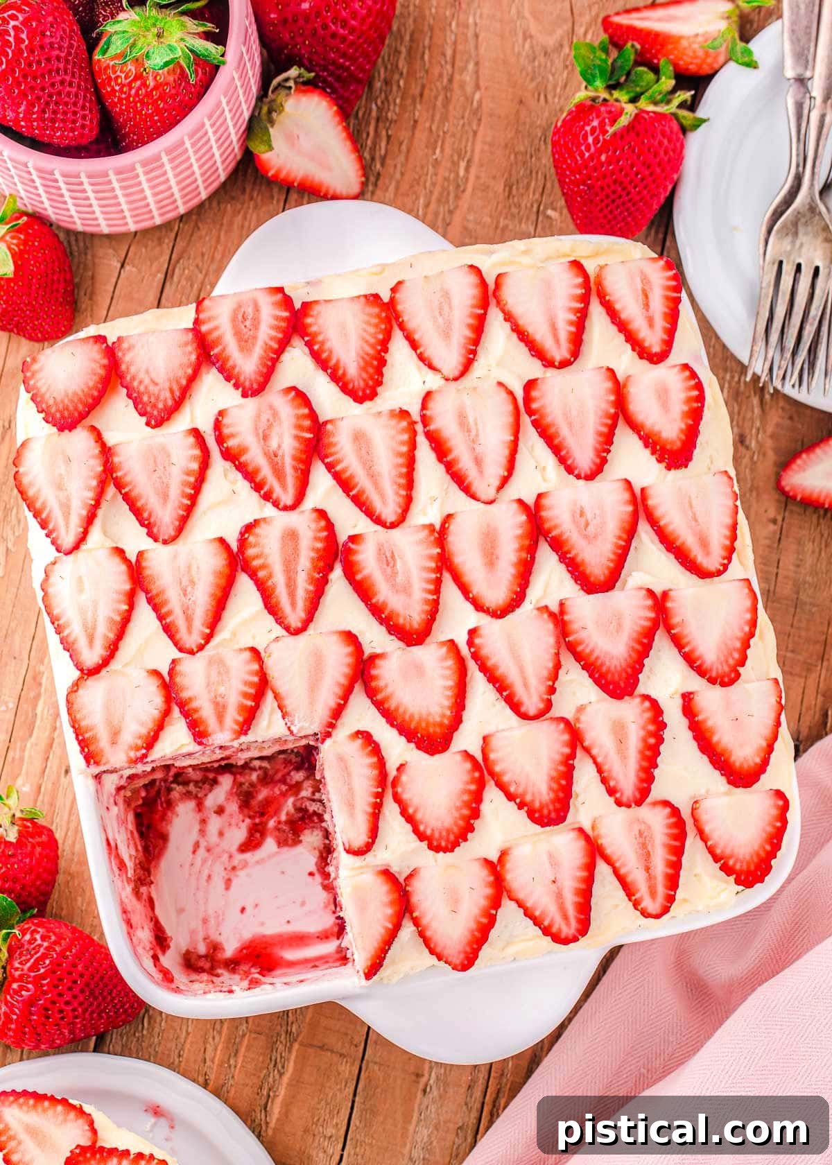Strawberry Dream Tiramisu 4 A top-down view of an assembled Strawberry Tiramisu in a white baking dish, resting on a wooden board, with one serving already removed.