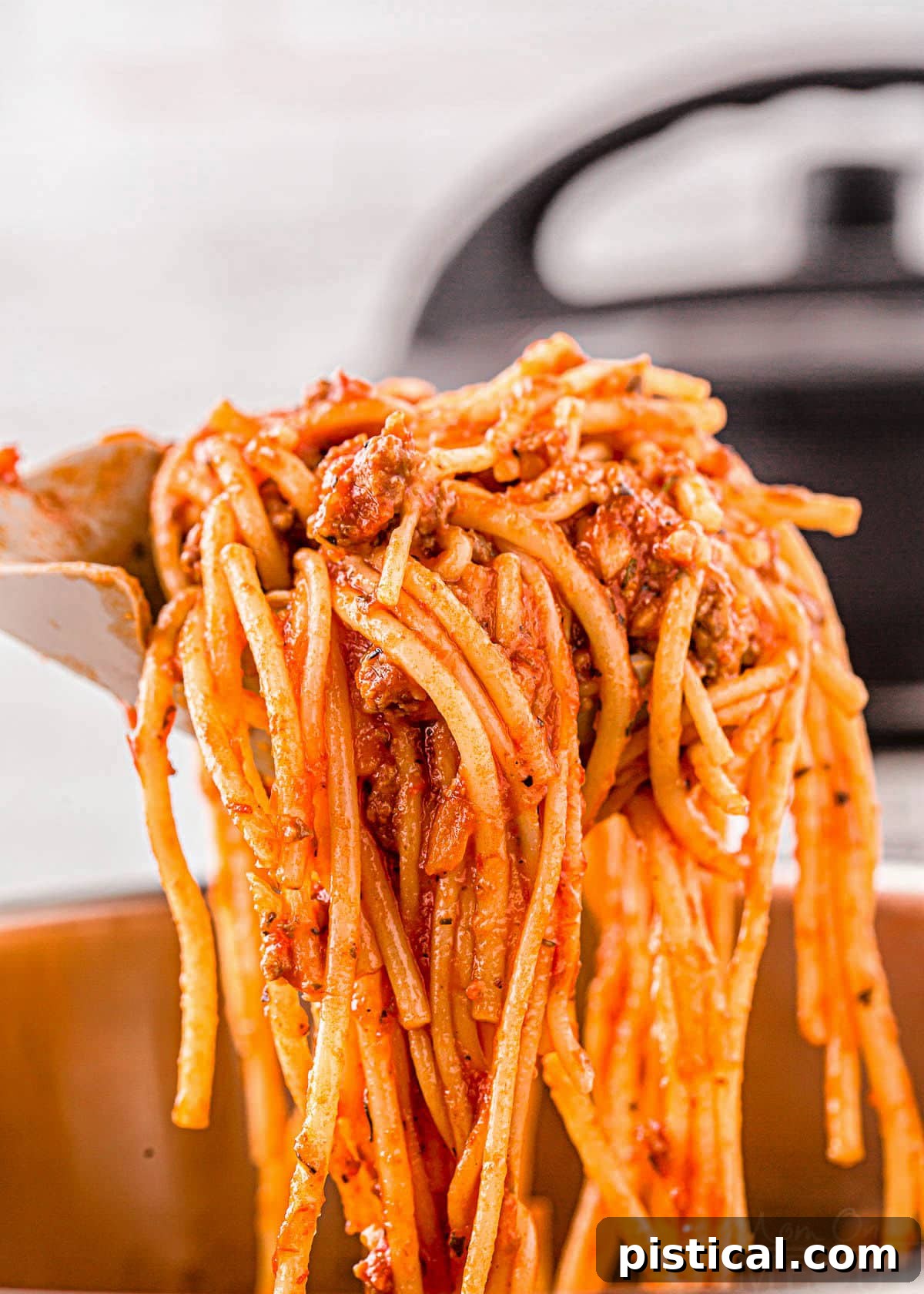 Effortless Instant Pot Spaghetti 3 scoop of instant pot spaghetti with the sauce mixed in held up over the instant pot.
