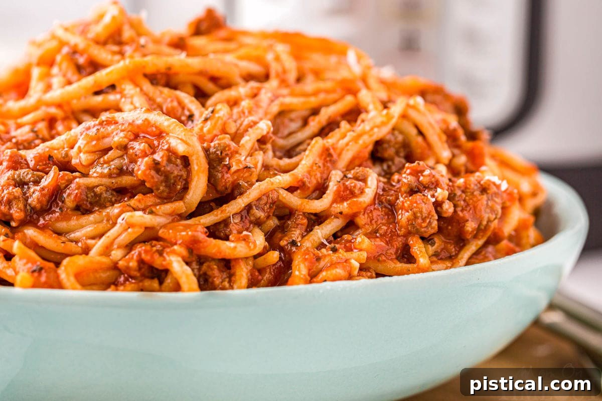 Effortless Instant Pot Spaghetti 6 large aqua serving bowl generously filled with spaghetti and meat sauce.
