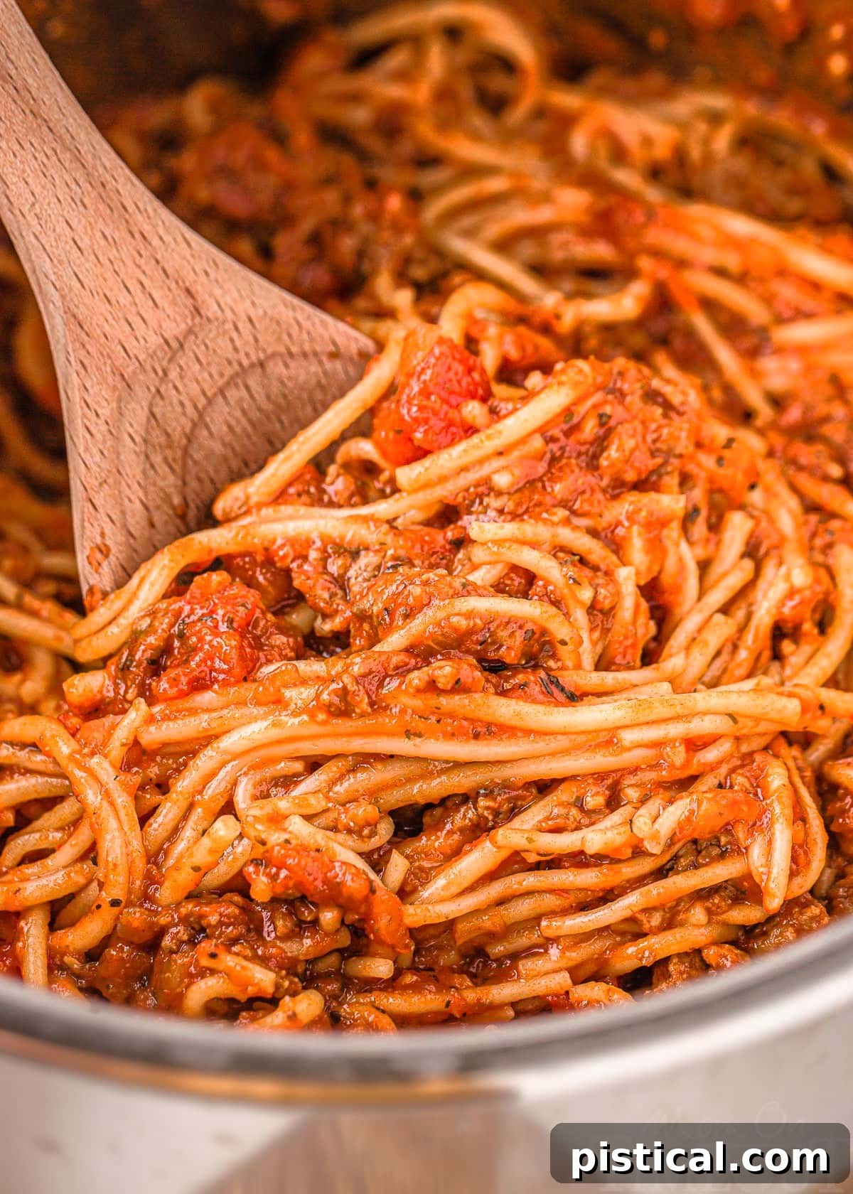 Effortless Instant Pot Spaghetti 7 close up look at instant pot with spaghetti in it ready to be served with a wooden spoon.